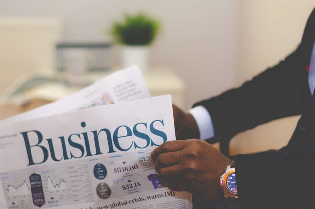 A businessman in a suit reading Business newspapers.