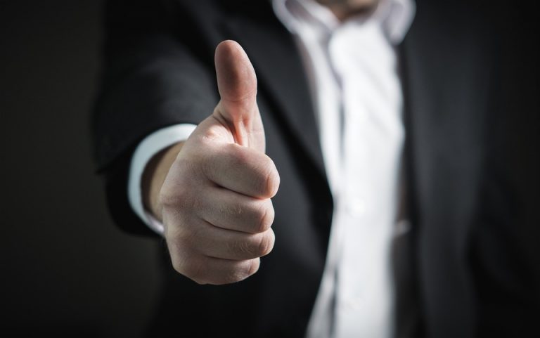 A man in a suit showing thumb up for the best cities in New Hampshire for your comany's HQ.