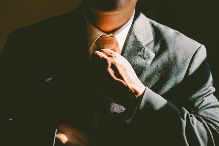 A man in a suit putting on a tie and getting ready to go to work in one of the top Ontario cities for job seekers.