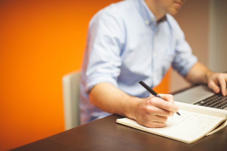 A man doing research on his laptop and making notes before starting a business in Philadelphia.